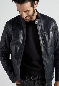 Marinblå läderjacka med en figursydd design, som har fodrade axelpartier, hög krage och blixtlåsfickor; slät textur.