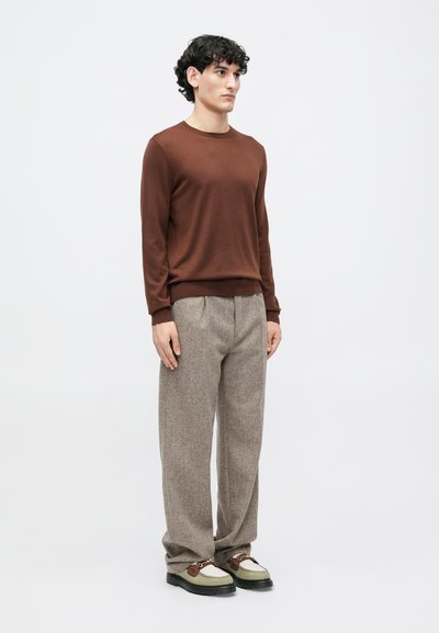 Suéter de malha castanha, calças em tweed cinza e sapatos multicoloridos. Textura suave, corte descontraído. Design simples sem padrões ou acentos.
