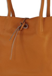 Leder-Tragetasche in Orange mit strukturiertem Material, zwei Griffen und einem grauen Kordelzug an der Oberseite als Verschlussmechanismus.