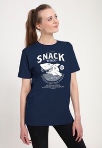 Marinblå bomulls t-shirt med en vit grafik som har en hajillustration och fet text som säger "SNACK ATTACK." Avslappnad design med korta ärmar.
