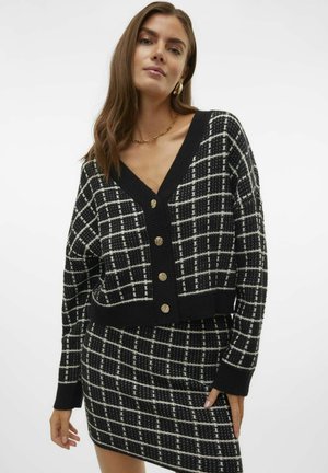 Zwart-witte geruite gebreide cardigan met een diepe V-hals en knopen in goudkleur. Geweven stof, cropped pasvorm en lange mouwen.