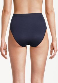 Donna che indossa lingerie blu navy a vita alta, mostrata di spalle su uno sfondo bianco semplice.