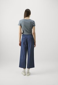 Top bluetta a maniche corte abbinato a pantaloni larghi navy. Sneakers bianche e calze lunghe fino alla caviglia completano l'outfit. Design semplice, dettagli minimi.