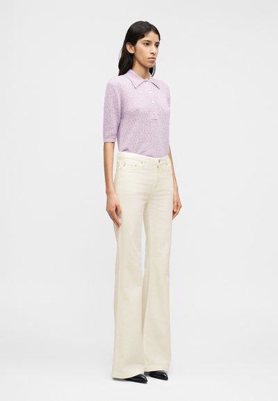 Εφαρμοστό πλεκτό πόλο με κοντά μανίκια σε λεβαντί απόχρωση  και γιακά, σε συνδυασμό με ψηλόμεσο κρεμ παντελόνι φαρδιάς γραμμής και μαύρα παπούτσια με μυτερή μύτη.