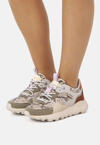 Zapatillas deportivas con un patr�ón texturizado de piel de serpiente en beige y gris, con una suela acolchada, detalles en lavanda y cordones grises.