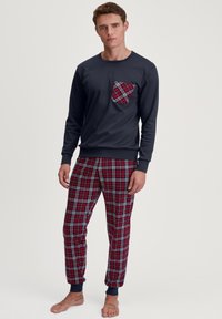 Marineblauw longsleeve shirt met een geruite zak, gecombineerd met rode geruite broek met blauwe en witte accenten. Gemaakt van katoen, ontspannen pasvorm.