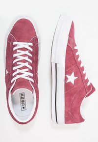 Burgundy suede high-top sneakers with white lace-up closure, white rubber sole, and a white star logo on the side. Textured surface.