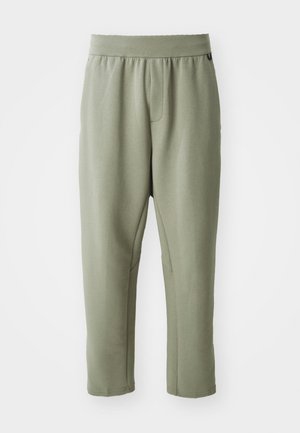 Light olive green tapered pants made of soft fabric, featuring an elastic waistband, a front pocket, and subtle stitching details.