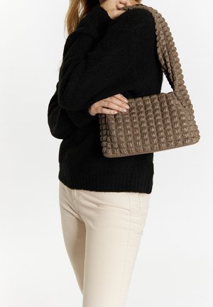 Sac à main marron texturé avec un design matelassé et une longue bandoulière, associé à un pull en maille noir, présentant une forme simple et des couleurs neutres.
