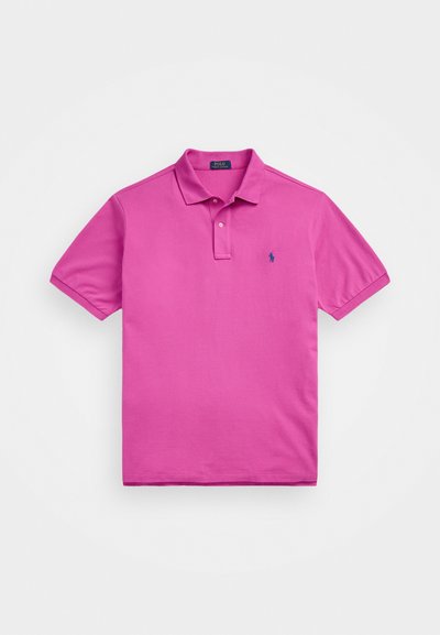 Rozā kokvilnas polo krekls ar klasisku apkakli, īsām piedurknēm un mazu zilu logotipu kreisajā krūtī. Gluda tekstūra.