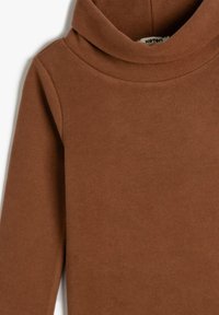 Suéter marrón de manga larga con cuello alto, con costura del cuello visible y textura acanalada, hecho de una suave tela de punto.