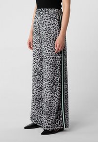 Spodnie z szerokimi nogawkami w panterkę w odcieniach szarości, z elastycznym pasem i zielonymi paskami po bokach, wykonane z miękkiego, strukturalnego materiału.