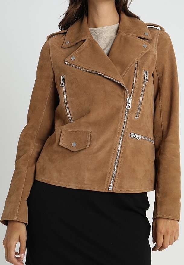 Hnědá suede motocyklová bunda se stříbrným kováním, asymetrickým předním zipem a několika zipovými kapsami. Má ramenní epauletky.