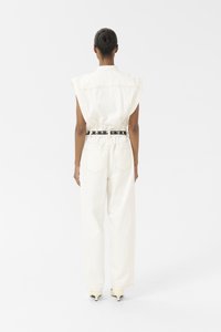 Combinaison sans manches blanche avec une taille cintrée et deux poches arrière. Le matériau semble lisse avec peu de détails de couture.
