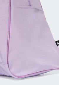 Sac à dos en tissu violet avec une texture lisse, doté d'une poche zippée et de piping rose contrastant le long des coutures.