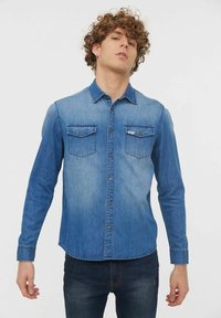 Chemise en denim, dégradé du bleu clair au bleu foncé, manches longues, fermeture à boutons sur le devant, deux poches poitrine avec rabats, détails de couture subtils.