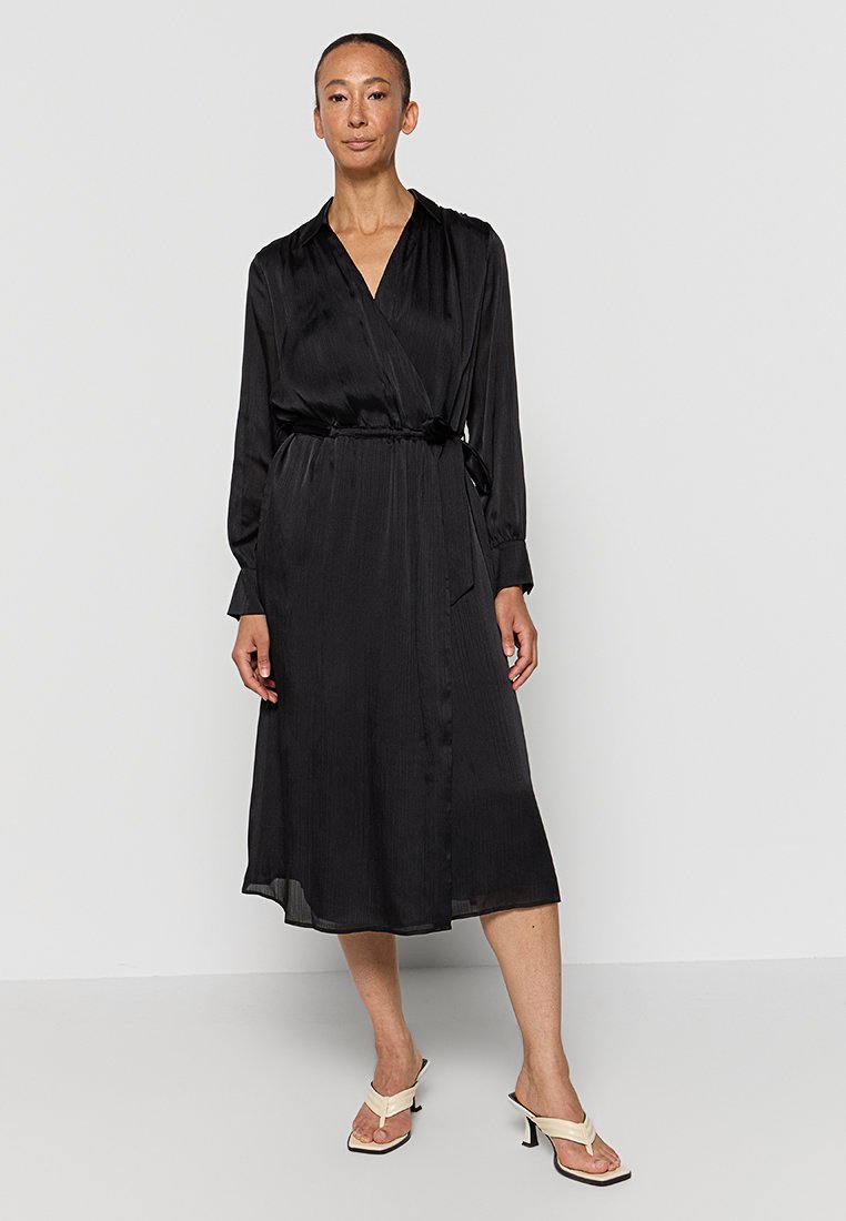 Schwarzes Wickelkleid mit langen Ärmeln, taillierter Schnitt und Midi-Länge. Weicher, fließender Stoff mit einem subtilen Glanz.