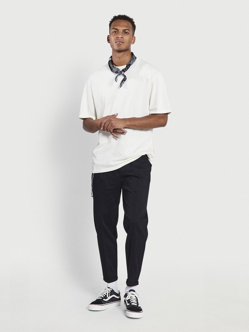 White oversized T-shirt, black scarf, black tapered pants, and black sneakers with white soles. Simple design, no patterns or graphics.