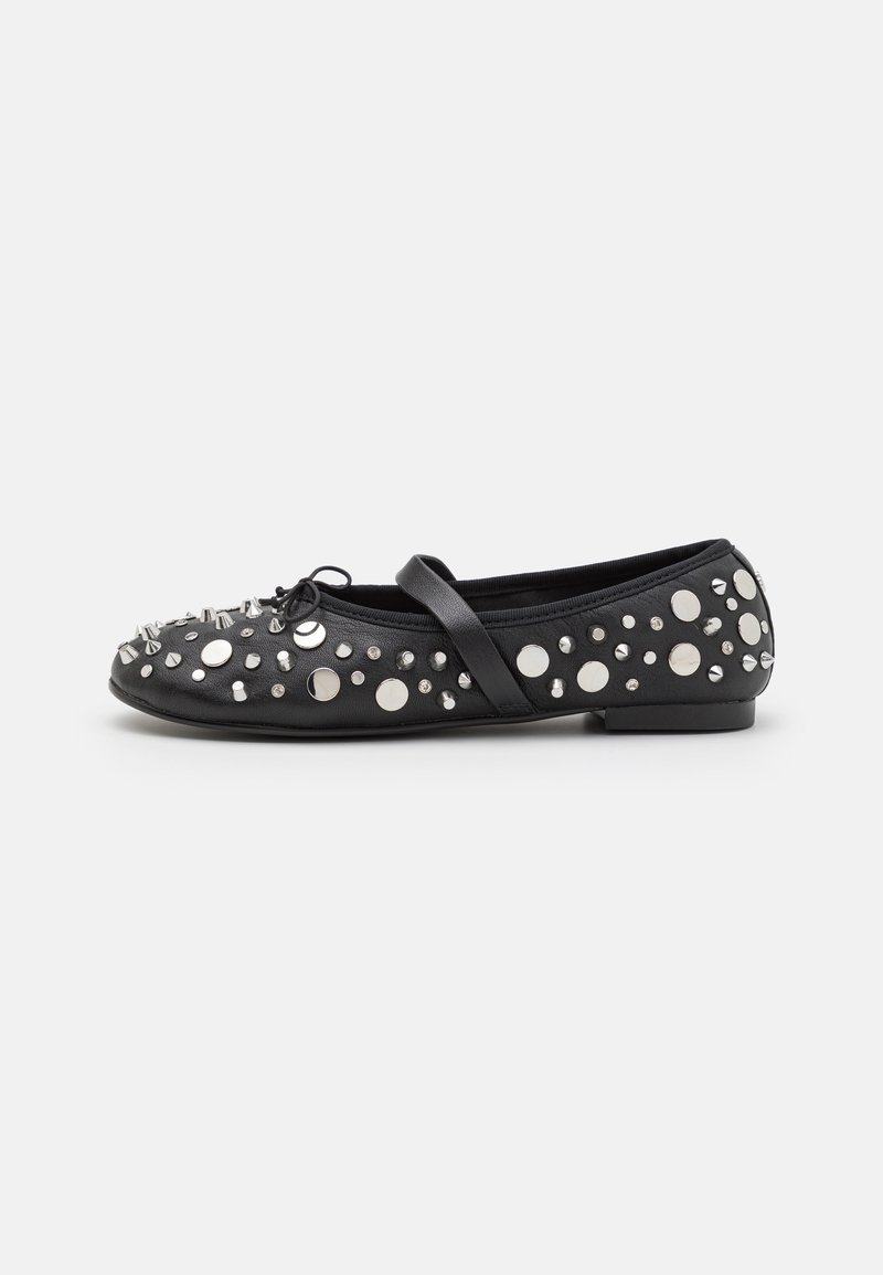 Chaussure plate noire avec des clous ronds et coniques argentés, un petit nœud à l'avant et une seule bride sur le dessus.