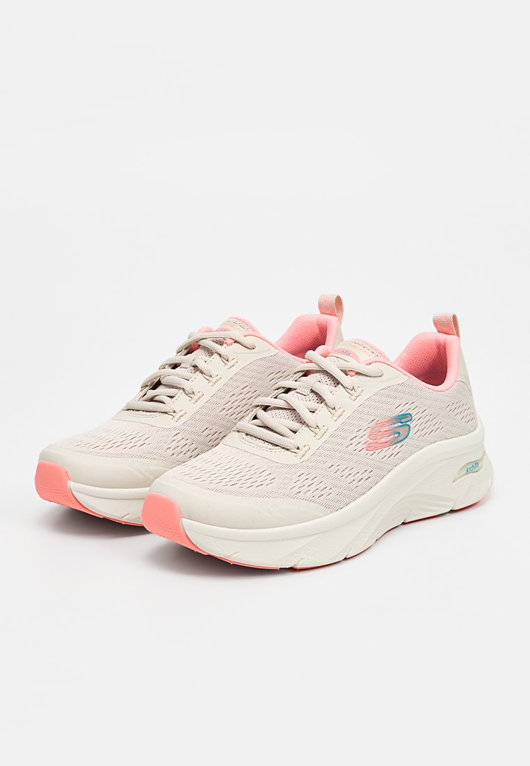 Zapatillas deportivas de color beige claro con acentos en rosa, parte superior de malla, diseño texturizado, suela acolchada y sistema de cordones para un ajuste seguro.