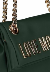 Sac en cuir vert foncé avec des anses en chaîne dorées et un lettrage doré texturé "LOVE MO" sur le rabat avant.