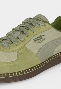 Χαμηλά παπούτσια Puma Palermo σε μπεζ και ελιά πράσινο, με υφή από ύφασμα και πάνελ από σουέτ, κορδόνια με σχέδιο και καφέ ραμμένη σόλα.