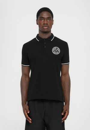 Black polo shirt with white trim, featuring a circular logo on the chest. Made of solid fabric with a classic collar and short sleeves.