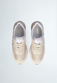 Scarpe sportive beige in materiali mesh e suede, con punta rotonda, lacci prominenti e dettaglio logo su un lato. Suola liscia e interno imbottito.