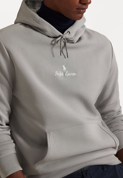 Hoodie cinza claro com cordão, textura ribada, bolso frontal e logótipo bordado branco a dizer "Ralph Lauren". Design suave e casual.