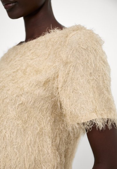 Top beige testurizzato con maniche corte, realizzato in materiale peloso. Presenta una vestibilità morbida e un collo alto. Nessuna chiusura o disegno visibile.