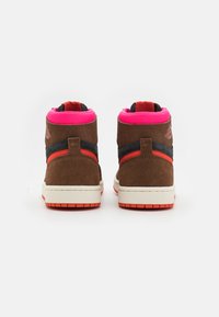 High-top sneakers in brown suede with black and orange accents. Pink padded collar and white midsole. Textured rubber outsole.
