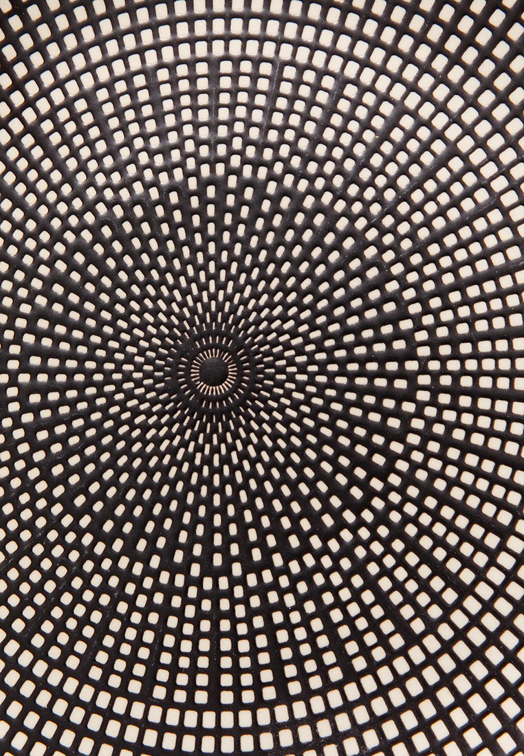 Patrón circular con cuadrados concéntricos en negro y crema, creando un diseño radial. La textura parece suave con bordes definidos.