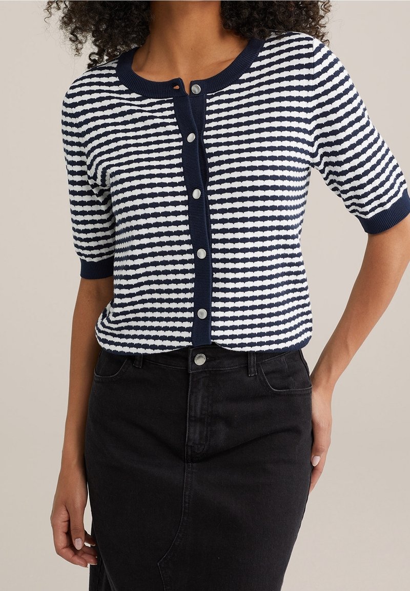 Marinblå och vit randig kortärmad cardigan med rund halsringning och knappstängning, tillsammans med en svart denimkjol.