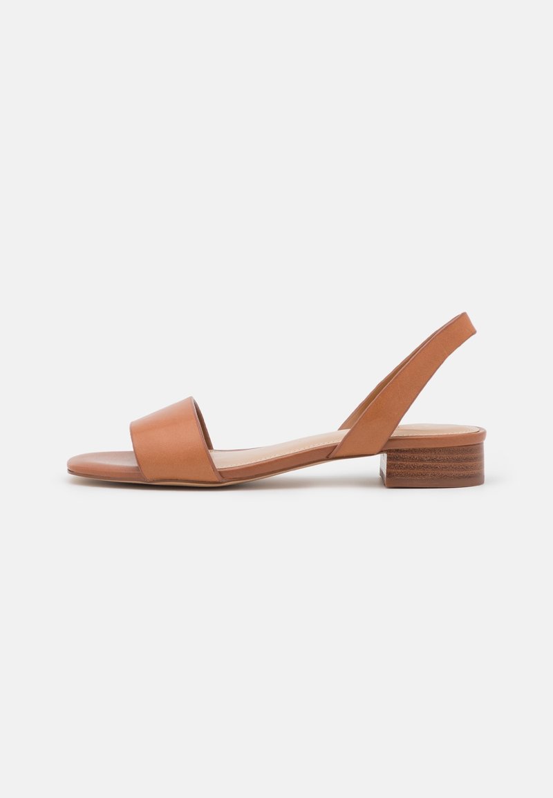 Sandale à bride arrière en cuir tan avec une large bride frontale et un petit talon bloc. Texture lisse avec un design minimaliste et un détail de talon en bois.