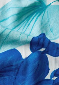 Blommigt tyg med stora blå och turkosa blommor på en vit bakgrund. Mjuk textur och flödande design.