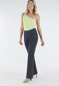 Mustat kflarehousut etutaskuilla, yhdistettyinä ribattuun yhden olkapään limen vihreään yläosaan ja vihreisiin nauhaketjuihin korkokenkiin.