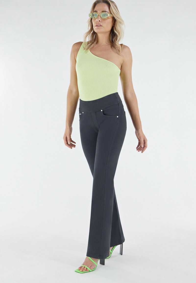 Mustat kflarehousut etutaskuilla, yhdistettyinä ribattuun yhden olkapään limen vihreään yläosaan ja vihreisiin nauhaketjuihin korkokenkiin.