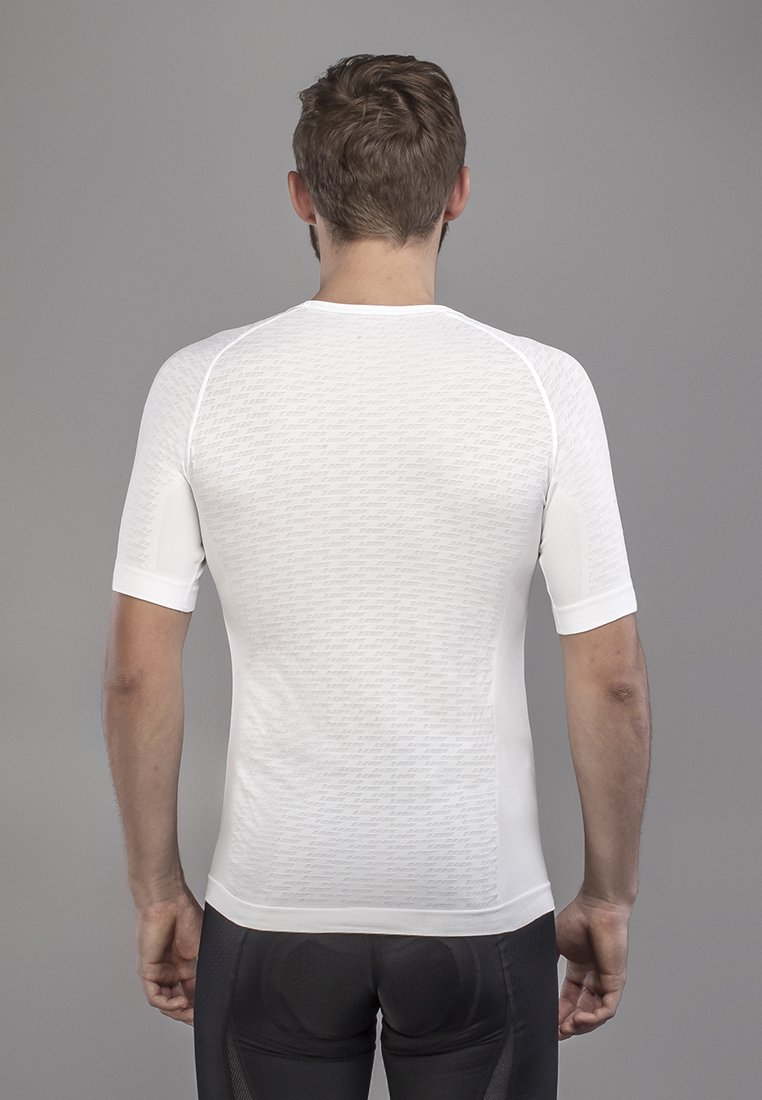 Ein Mann trägt ein enges weißes kurzärmeliges Fahrradtrikot und schwarze gepolsterte Fahrradhosen, von hinten gesehen vor einem grauen Hintergrund.