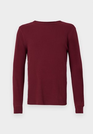 T-shirt à manches longues côtelé de couleur bordeaux profond, avec un col rond et des poignets ajustés. Texture lisse, sans motifs ni accents visibles.