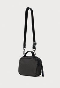 Čierna nylonová crossbody taška s nastaviteľným popruhom, horným držadlom a striebornými kovovými prvkami. Obsahuje zips a elegantný obdĺžnikový tvar.