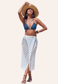 Modrý trojúhelníkový bikiny top spárovaný s průsvitnou bílou sukni s diamantovým vzorem. Doplněno slamáčkem a vrstvenými náhrdelníky.