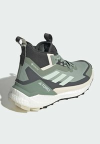 Groene en grijze sportieve schoen met een hoge top, met een textiel bovenwerk, een gevoerde witte tussenzool en een zwarte traction buitenzool.