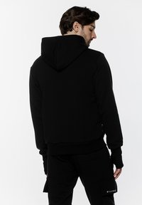 Czarna bluza z kapturem wykonana z miękkiego materiału, z kapturem na sznurek i ściągaczami przy rękawach. Zaprojektowana w krótkim kroju, bez wyraźnych logo ani wzorów.