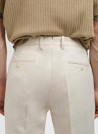 Beige broek met een getailleerde pasvorm, voorzien van achterzakken met knopen en een gladde textuur, aangevuld met een ribbelige, beige top.