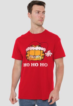 Red cotton T-shirt featuring a cartoon cat in a Santa hat and "HO HO HO" text, with a smooth texture and casual design.