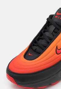 Nike Air Max 97 tornacipők narancs-fekete átmenetes felsőrésszel, fekete fűzőkkel és piros kiemelt logóval. Texturált szövet és gumitalp.