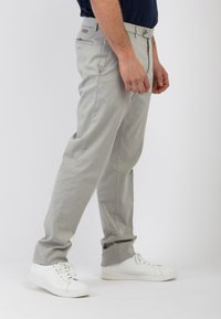 Chinos grigio chiaro con taglio dritto, in cotone, con tasche anteriori e posteriori e un dettaglio a bottone in vita. Abbinati a sneakers bianche.