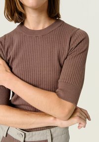 Brown ribbed knit short-sleeve top with a round neckline. Textured fabric features vertical stripes and a fitted silhouette.