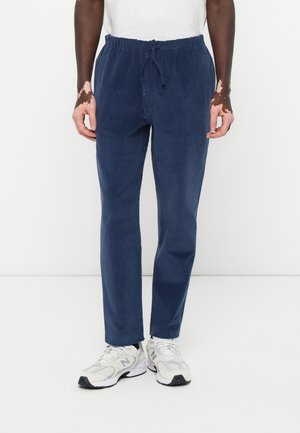 Navy blue elastic waist pants with adjustable drawstring, featuring a relaxed fit and side pockets. Material appears soft and textured.