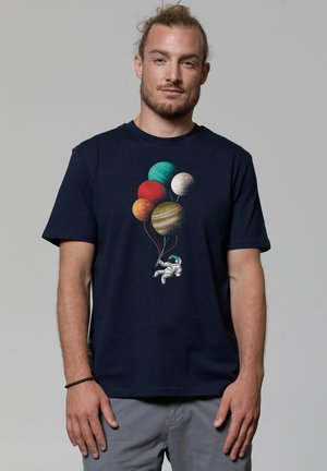 Navy blue cotton t-shirt featuring a graphic of an astronaut holding colorful planet balloons in various shades. Short sleeves, relaxed fit.